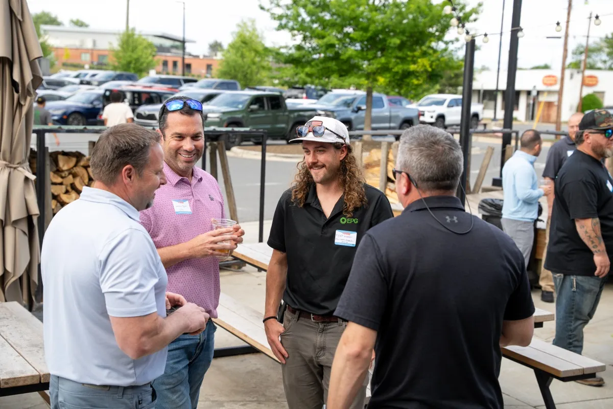 A group of attendees laughing outdoors with trucks behind